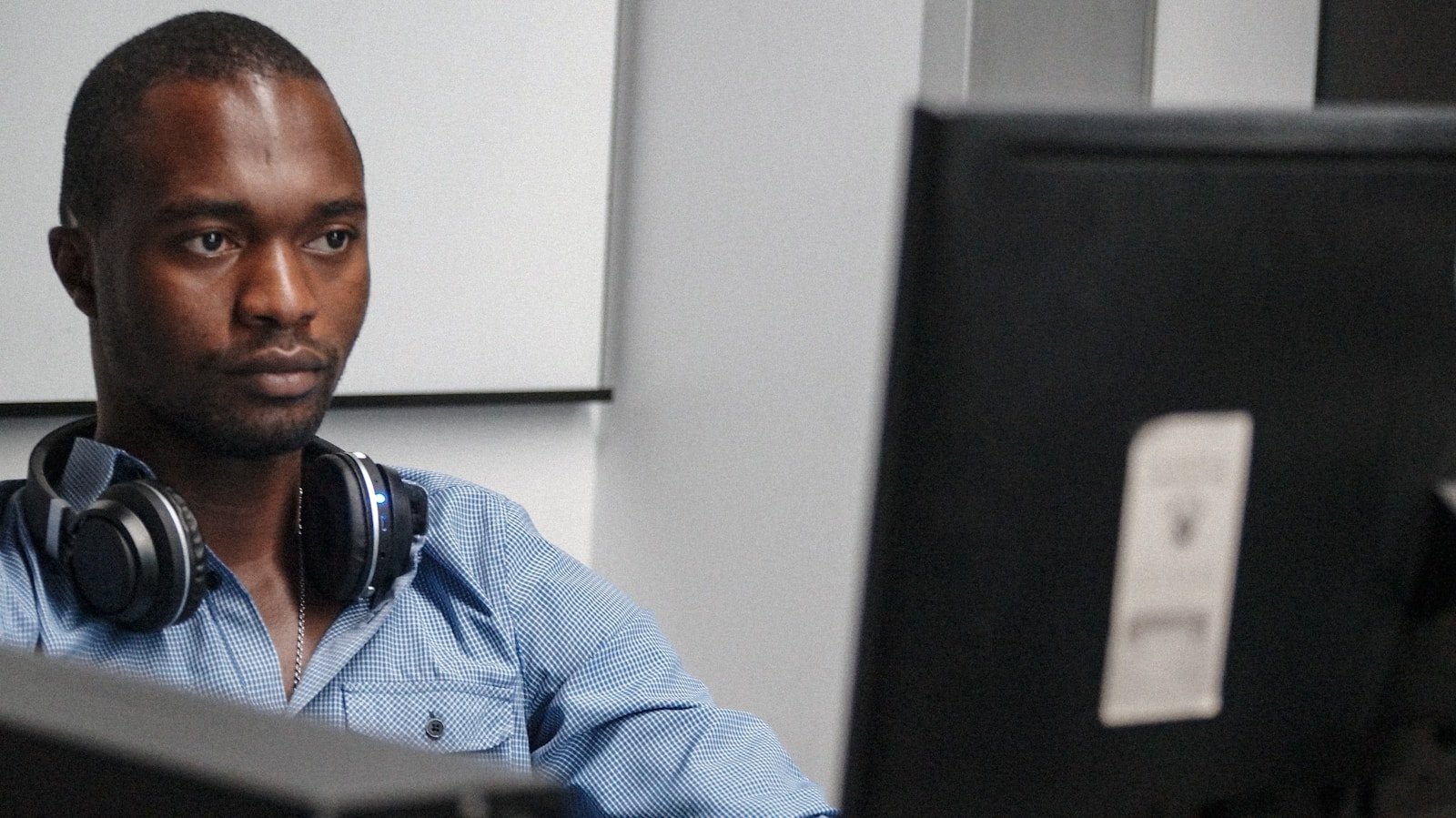 man sitting facing monitor inside room