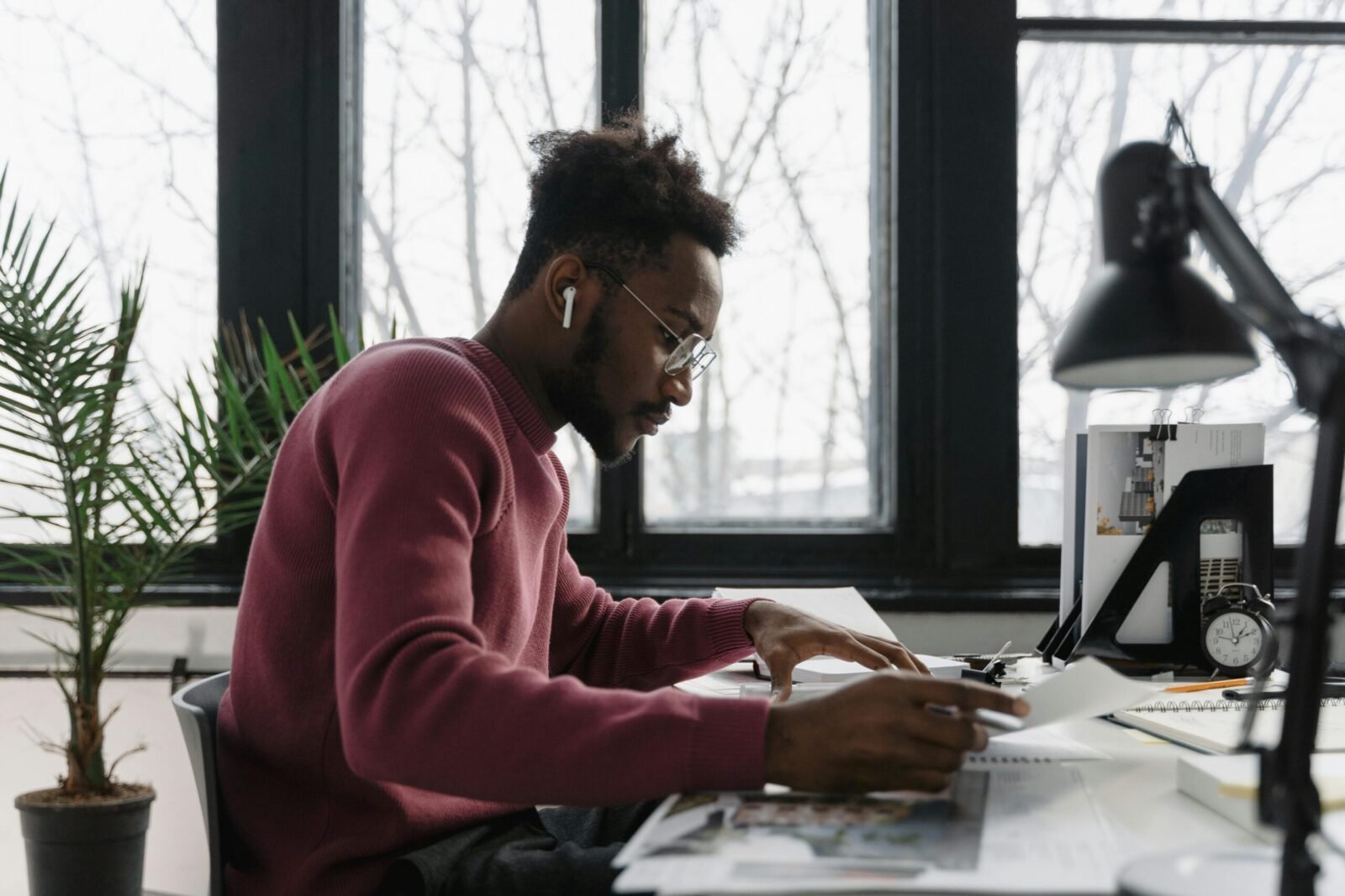 A professional architect engrossed in drawing plans at his desk with modern tools in a bright office.